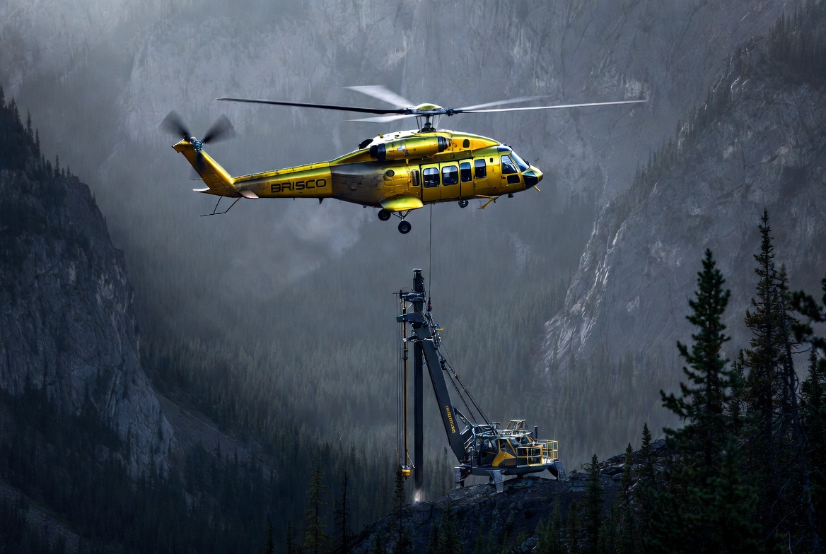 Brisco helicopter longlining a drill rig onto a remote mountain ridge